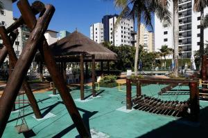 a playground with a swing set and a straw umbrella at Condomínio Acqua de Riviera - Módulo 3 in Riviera de São Lourenço