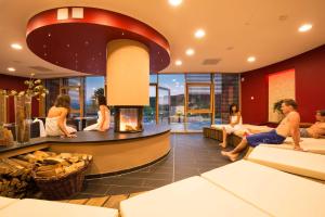 a group of people sitting in a living room with a fireplace at Panoramabungalow _50_ im Feriendor in Truppach
