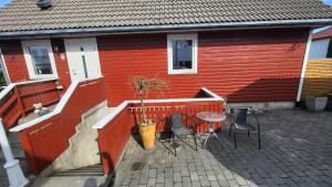 een rood huis met een tafel en stoelen op een patio bij Flott leilighet i stille og rolig område, med gratis privat parkering! in Stavanger