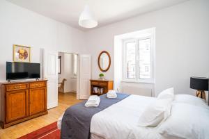 a white bedroom with a bed and a flat screen tv at LAUS II, Lovely Apartment in Old town Dubrovnik in Dubrovnik