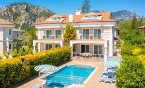 a house with a swimming pool and two lawn chairs at Villa Günsu in Ortaca