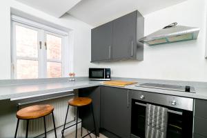 a kitchen with gray cabinets and two stools at The Oldtown Lodge in Stevenage