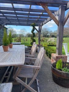 a wooden picnic table and chairs under a pergola at Abbey Green Farm in Wem