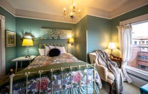 a bedroom with green walls and a bed and a chandelier at Clementine's Guest House & Vacation Rentals in Astoria, Oregon