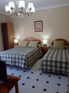 a bedroom with two beds and a chandelier at Casa Angelita in Catí