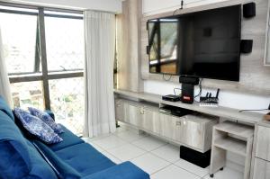 uma sala de estar com um sofá azul e uma televisão de ecrã plano em Aconchegante Apt na Praia de Pajuçara !Gales 907 com piscina na cobertura e vaga de garagem - Gales de Pajuçara 907-Wifi 500 mg-Pertinho de Tudo em Maceió
