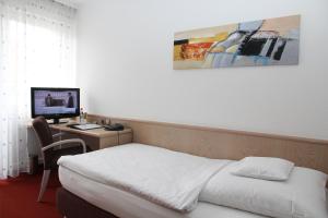 a hotel room with a bed, desk and television at Hotel Vetter in Nürtingen