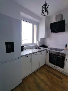 a kitchen with white cabinets and a window at Apartament przy Zamku Krzyżackim in Malbork