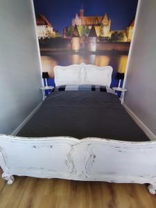 a bed in a room with a white bed frame at Apartament przy Zamku Krzyżackim in Malbork