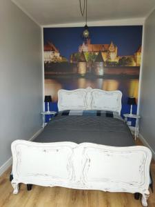 a bedroom with a white bed with a painting on the wall at Apartament przy Zamku Krzyżackim in Malbork