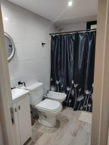 a bathroom with a toilet and a black shower curtain at Duplex Pinamar norte frente al bosque in Pinamar