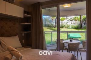 a bedroom with a bed and a balcony with a table at Qavi - Apto em Resort Beira Mar Cotovelo #InMare43 in Parnamirim