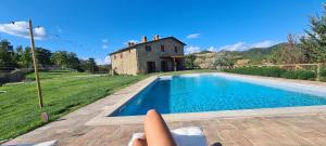 a person laying on the ground next to a swimming pool at Villa Convento Pietralunga in Pietralunga