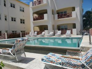 - une piscine avec chaises longues et un bâtiment dans l'établissement Miramar Villas Resort, à San Pedro