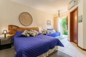 a bedroom with a bed with a blue comforter at Pousada Penareia Floripa in Florianópolis