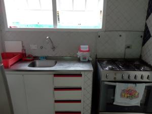 a small kitchen with a sink and a stove at Paraíso de Verão - Disfrute final de semana em Casa Exclusiva com piscina, sinuca e churrasqueira Aluguel para temporada em Riviera de São Lourenço in Bertioga