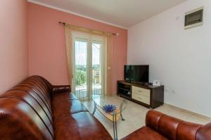 a living room with a leather couch and a television at Apartmani Lorena in Okrug Gornji