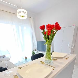 un jarrón de flores rojas sentado en una mesa en Apartament Perłowy Wellness - Laguna Beskidów, en Bierna