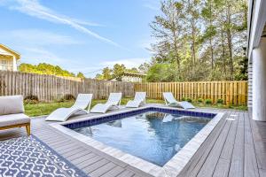 a swimming pool with white chairs and a fence at Between the Lake and the Ocean in Santa Rosa Beach
