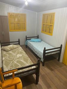 una camera da letto con due letti e una sedia di Casa com piscina e salão de jogos para aluguel de temporada e finais de semana em Torres/RS. a Torres