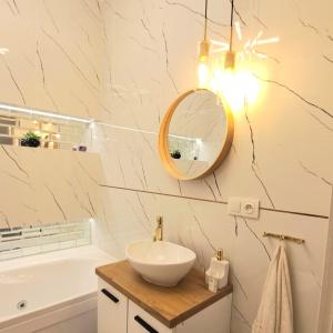W łazience znajduje się umywalka, lustro i wanna. w obiekcie Apartament Perłowy Wellness - Laguna Beskidów w mieście Bierna
