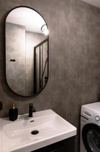 a bathroom with a white sink and a mirror at ClickTheFlat Conrada Apart Rooms in Warsaw