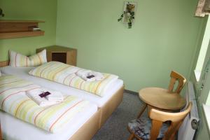 two twin beds in a room with a chair at Wellness Hotel Pension & Gaststätte Riedel in Kurort Oberwiesenthal
