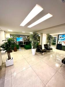 a lobby with chairs and plants in a building at Hotel Imperatriz in Telêmaco Borba