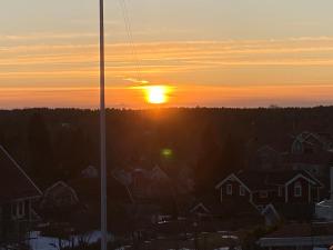 a sunset over a city with houses and a pole at Glamping Stay with Comfortable Beds and a Beautiful Garden in Kallfors, Stockholm near a Golf Course, Lakes, the Baltic Sea, Forests & Nature in Järna