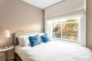 a bedroom with a bed with blue pillows and a window at Idyllic Islington Flat in London