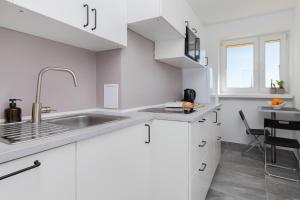 una cocina blanca con armarios blancos y fregadero en Family apartment with balcony Warszawska Gdynia by Renters, en Gdynia