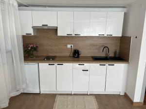 a white kitchen with white cabinets and a sink at Orłowo nadmorskie in Gdynia