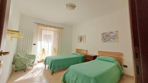 a bedroom with two green beds and a window at Casa TRICAGLIO in Barisciano