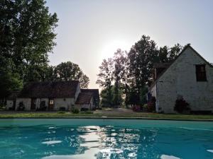 - une piscine en face d'une maison dans l'établissement L 'Aupinouse Chambre double Pivoine avec salle d'eau privative, à La Suze-sur-Sarthe
