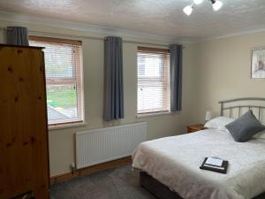 a bedroom with a bed and two windows at Bron Menai Guest House in Caernarfon