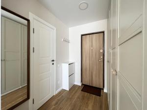 a hallway with white walls and a wooden door at Apartment near Outlet park by URBAN RENT in Vilnius