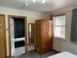 a bedroom with a wooden cabinet and a window at Bron Menai Guest House in Caernarfon
