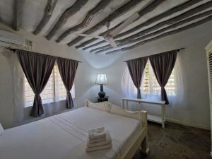 a bedroom with a white bed and two windows at Waridi House in Watamu
