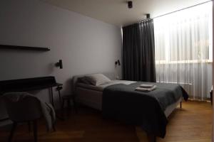 um quarto com uma cama, uma secretária e uma janela em Cozy apartment with underground parking em Vilnius