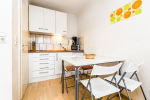 ケルンにあるWork and Stay Koeln Ostheimの白いキャビネット、テーブルと椅子付きのキッチンが備わります。