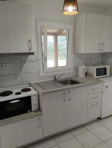 eine weiße Küche mit einer Spüle und einer Mikrowelle in der Unterkunft Studios Dimitraki in Skala Rachoniou