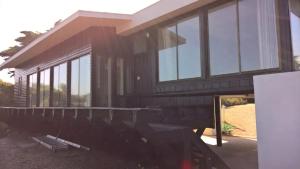 a house with glass windows on the side of it at Casa en la playa entre Pichidangui y Los Vilos in Los Vilos