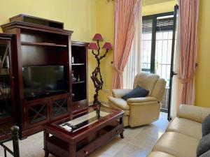 een woonkamer met een televisie, een bank en een tafel bij Apartamento Suite Alameda de Hercules in Sevilla