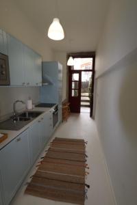 a kitchen with white cabinets and a kitchen rug on the floor at Rustic Silent Ensuites - Shared Kitchen - Self check in in Porto