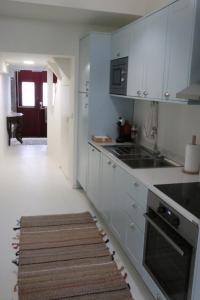 a kitchen with white cabinets and a kitchen rug at Rustic Silent Ensuites - Shared Kitchen - Self check in in Porto +11 photos