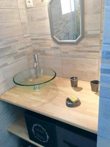 een badkamer met een glazen wastafel en een spiegel bij gite le ptit bleu maison totalement indépendant in La Tremblade