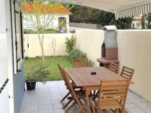 een houten tafel en stoelen op een patio met een grill bij gite le ptit bleu maison totalement indépendant in La Tremblade
