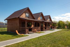 ein großes Holzhaus mit Stühlen im Gras in der Unterkunft MarkoweDomki,pl in Jantar