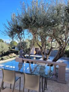 uma mesa e cadeiras com árvores e uma piscina em Maison avec piscine, oliviers, belle vue, au calme em Trans-en-Provence