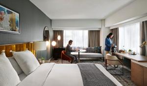 um quarto de hotel com uma cama e duas pessoas sentadas numa mesa em voco Chicago Downtown, an IHG Hotel em Chicago